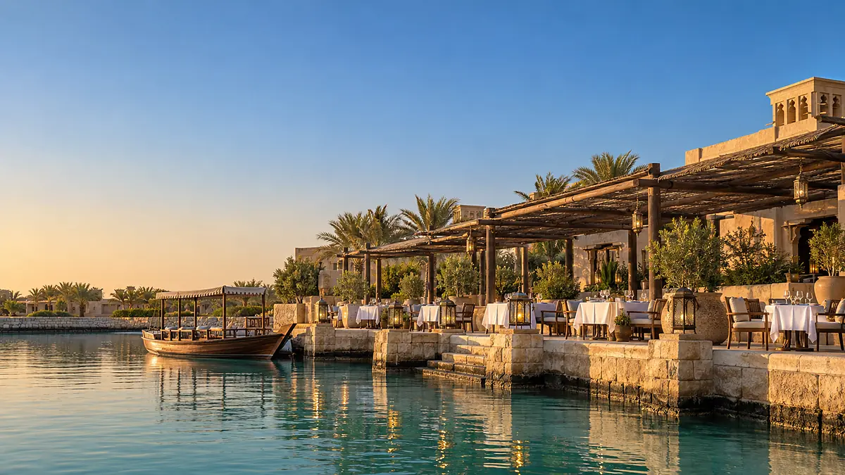 Tables laid along the arcade at Mawj, seen from the lagoon under a clear evening sky